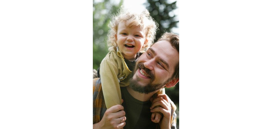 Vater mit Kind Vater trägt kleines Kind fröhlich auf dem Rücken