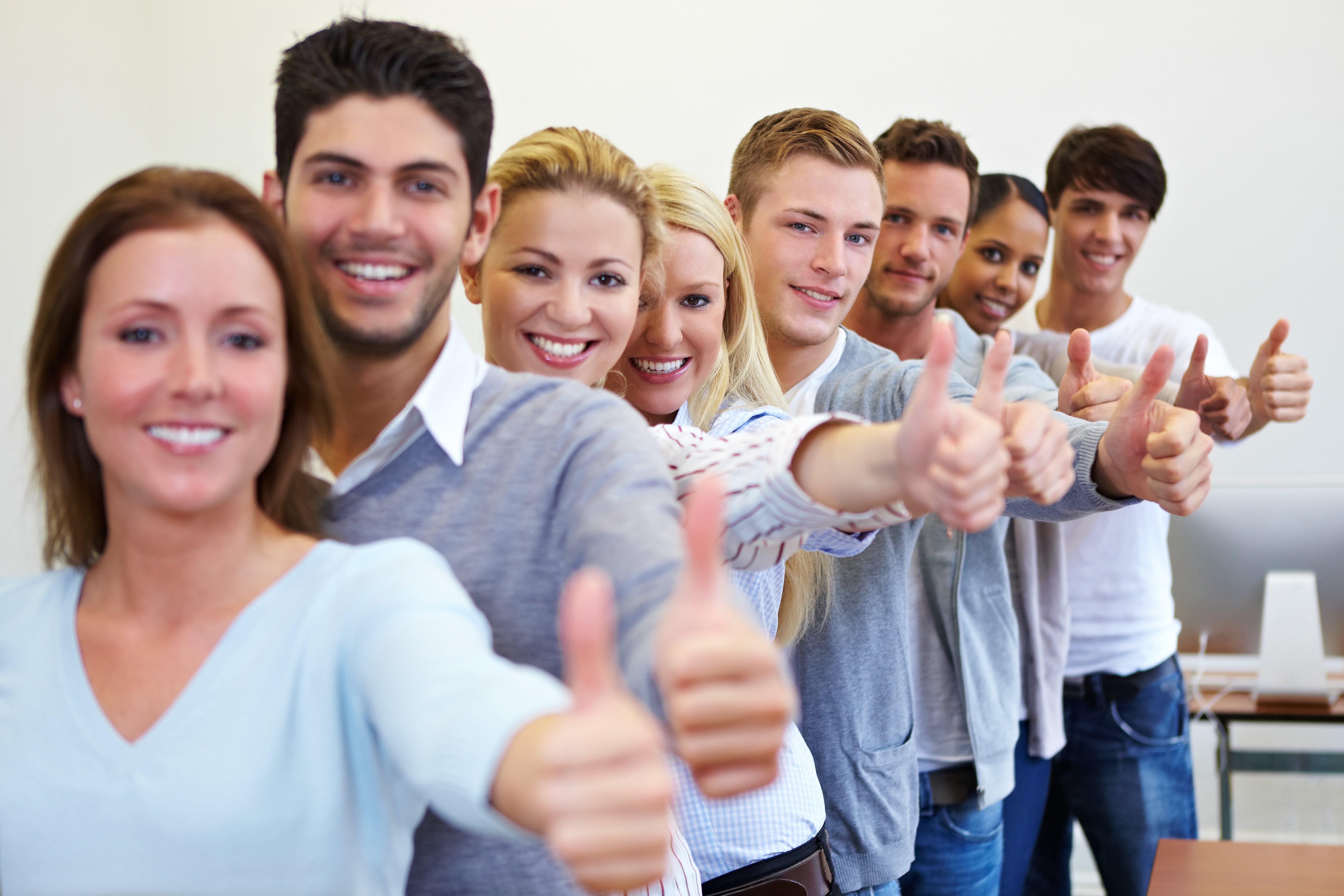 Viele Studenten halten Daumen hoch Viele Studenten halten Daumen hoch